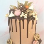 Chocolate drip cake decorated with macarons, mini doughnuts, ferrero rocher, fresh raspberries and popcorn