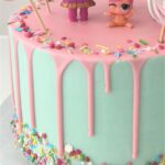 LOL Doll white chocolate drip cake with colourful sprinkles and meringue lollipops