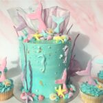 Mermaid Cake decorated with edible fondant tails and seashells with rice paper coral and matching cupcakes