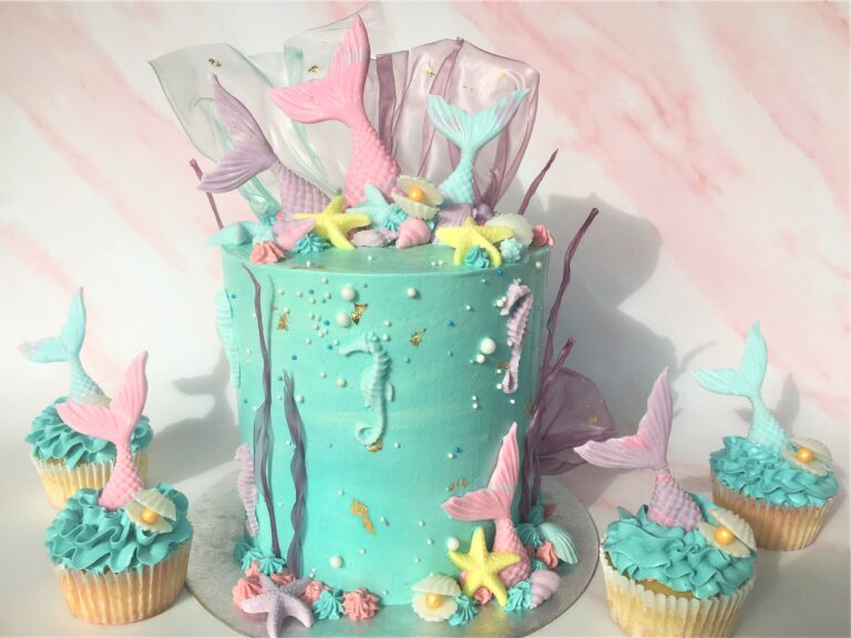 Mermaid Cake decorated with edible fondant tails and seashells with rice paper coral and matching cupcakes