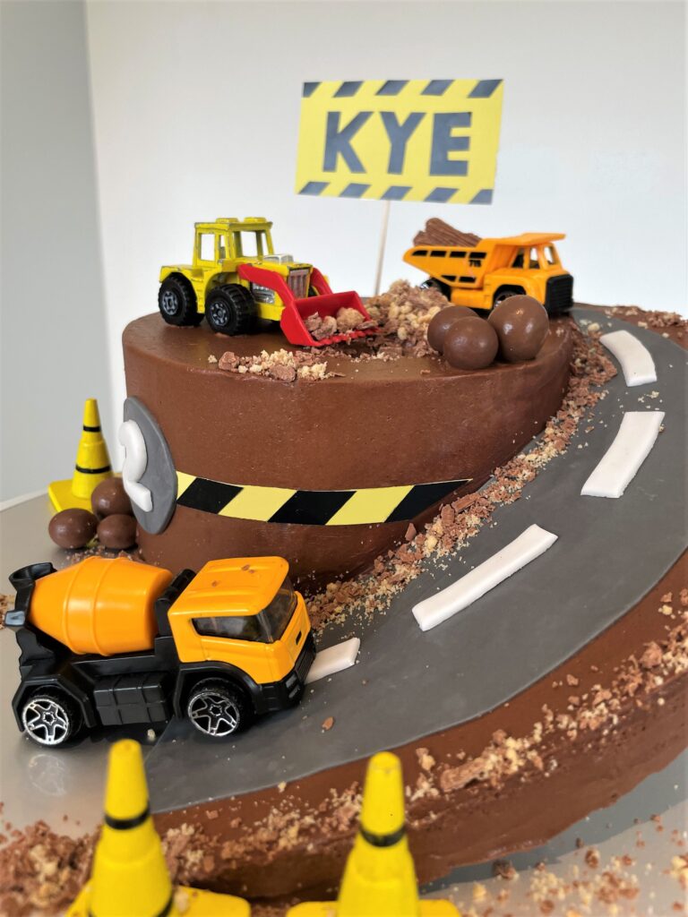 Digger Cake decorated with crushed biscuits and chocolate for a sand/mud effect and chocolate boulders