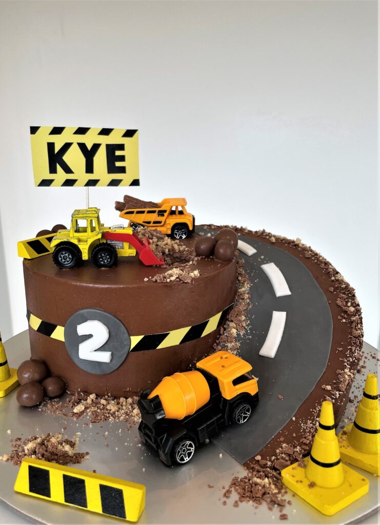 Digger Cake decorated with crushed biscuits and chocolate for a sand/mud effect and chocolate boulders