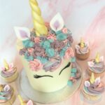 Decorated with swirls of colourful buttercream , fondant ears, lashes and golden horn