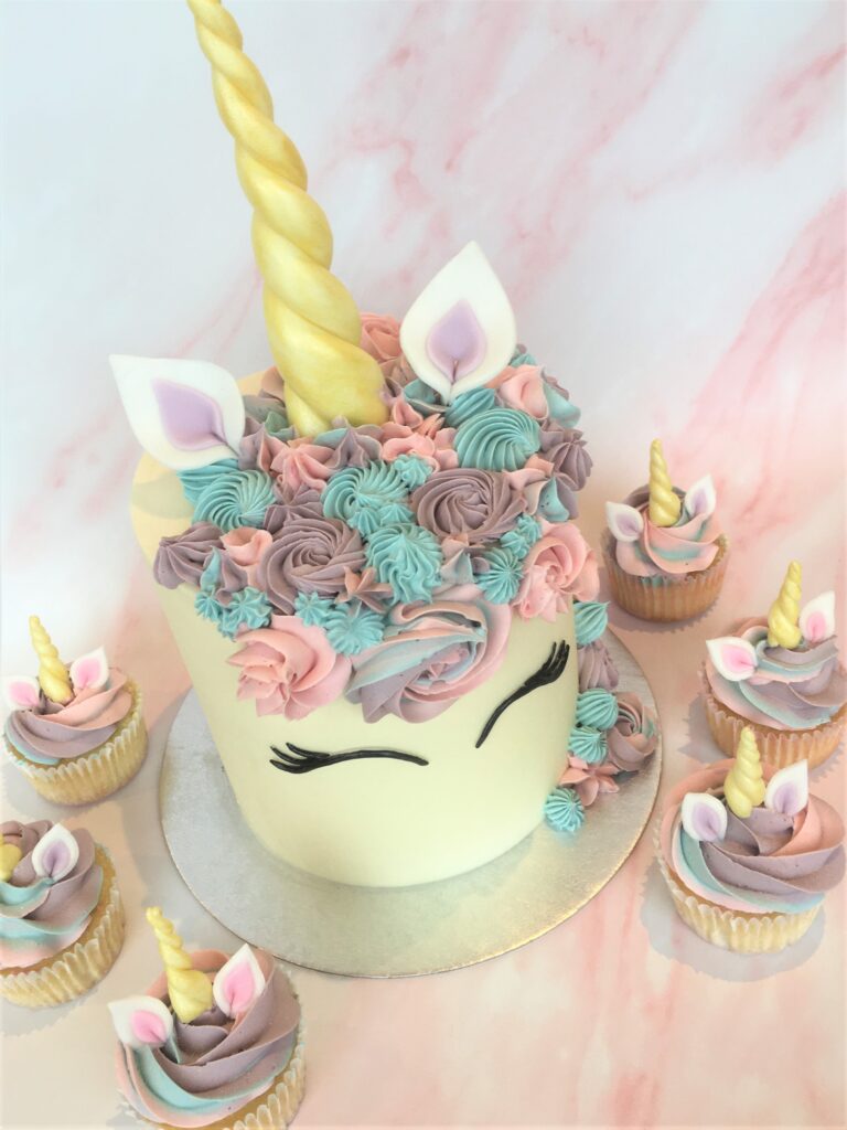 Decorated with swirls of colourful buttercream , fondant ears, lashes and golden horn