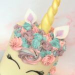 Unicorn cake with swirls of colourful buttercream and edible fondant ears and horn