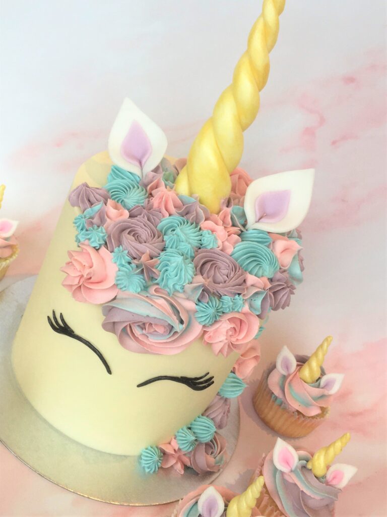 Unicorn cake with swirls of colourfule buttercream and edible fondant ears and horn