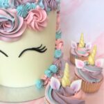 Unicorn cake with swirls of colourful buttercream and edible fondant ears and horn and matching cupcakes