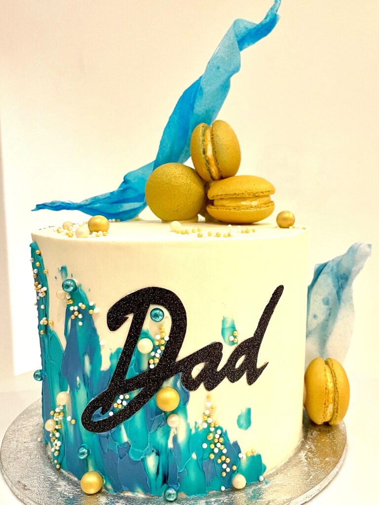 Abstract decorated cake with macarons and wafer paper sail