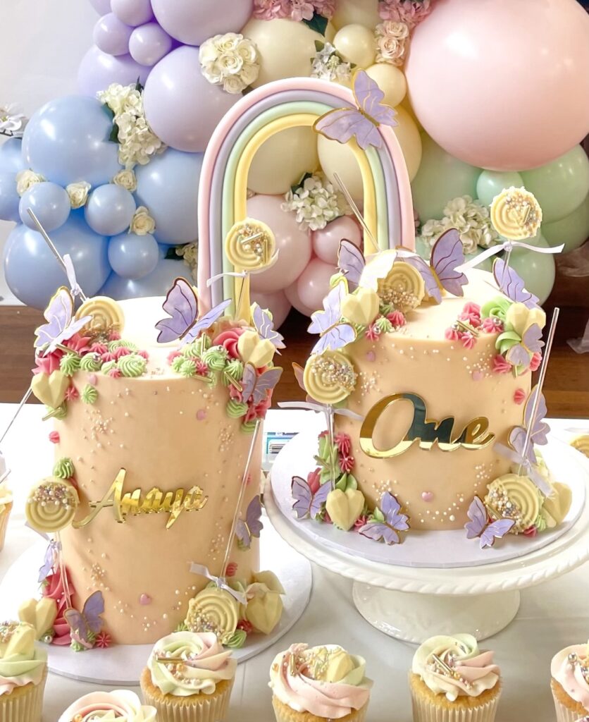 Double cake with connecting pastel rainbow. Decorated with chocolate hearts, lollies and butterflies